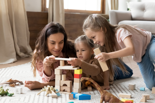 Smiling mixed race babysitter playing with children.